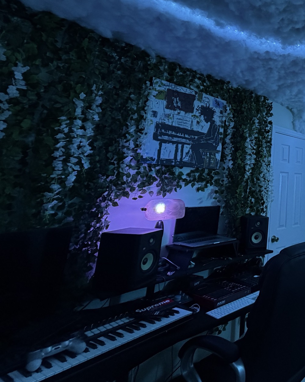 The producer desk at Rose Garden Studios: monitors, keyboard and drum pads under an ivy wall with white flowers.